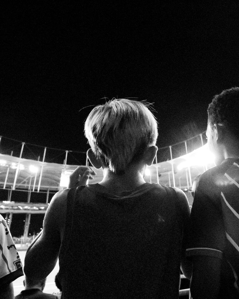 Young supporters watching a floodlit match from the stands