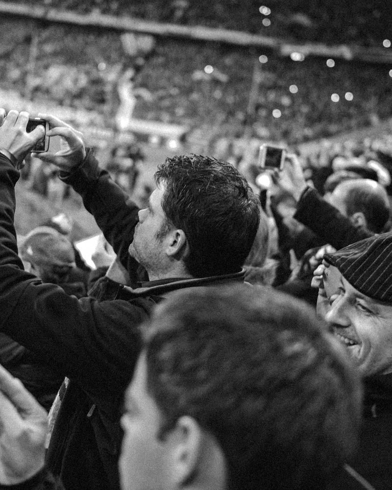 Supporters filming and smiling together in a packed stand
