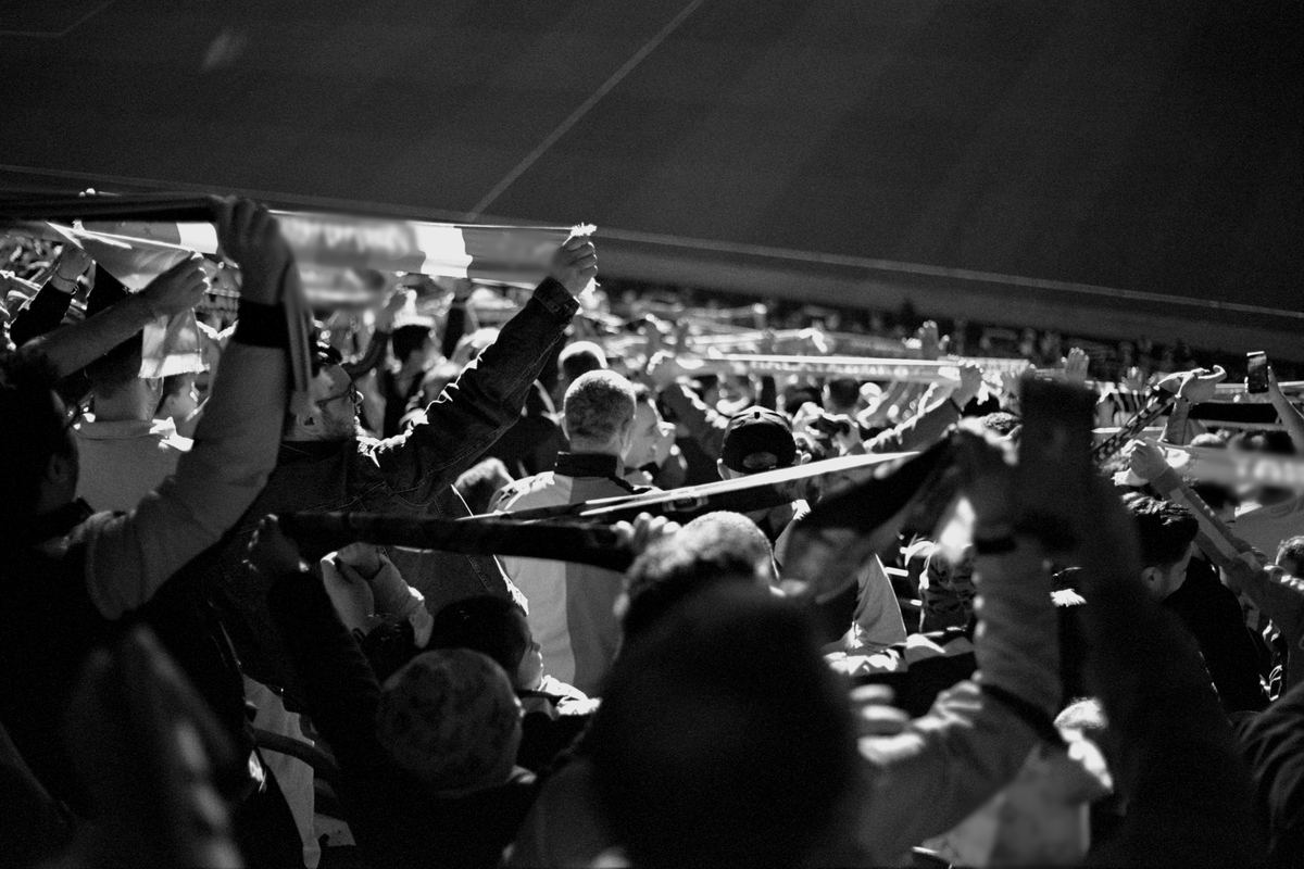 Supporters holding their scarves high in a packed stand at night